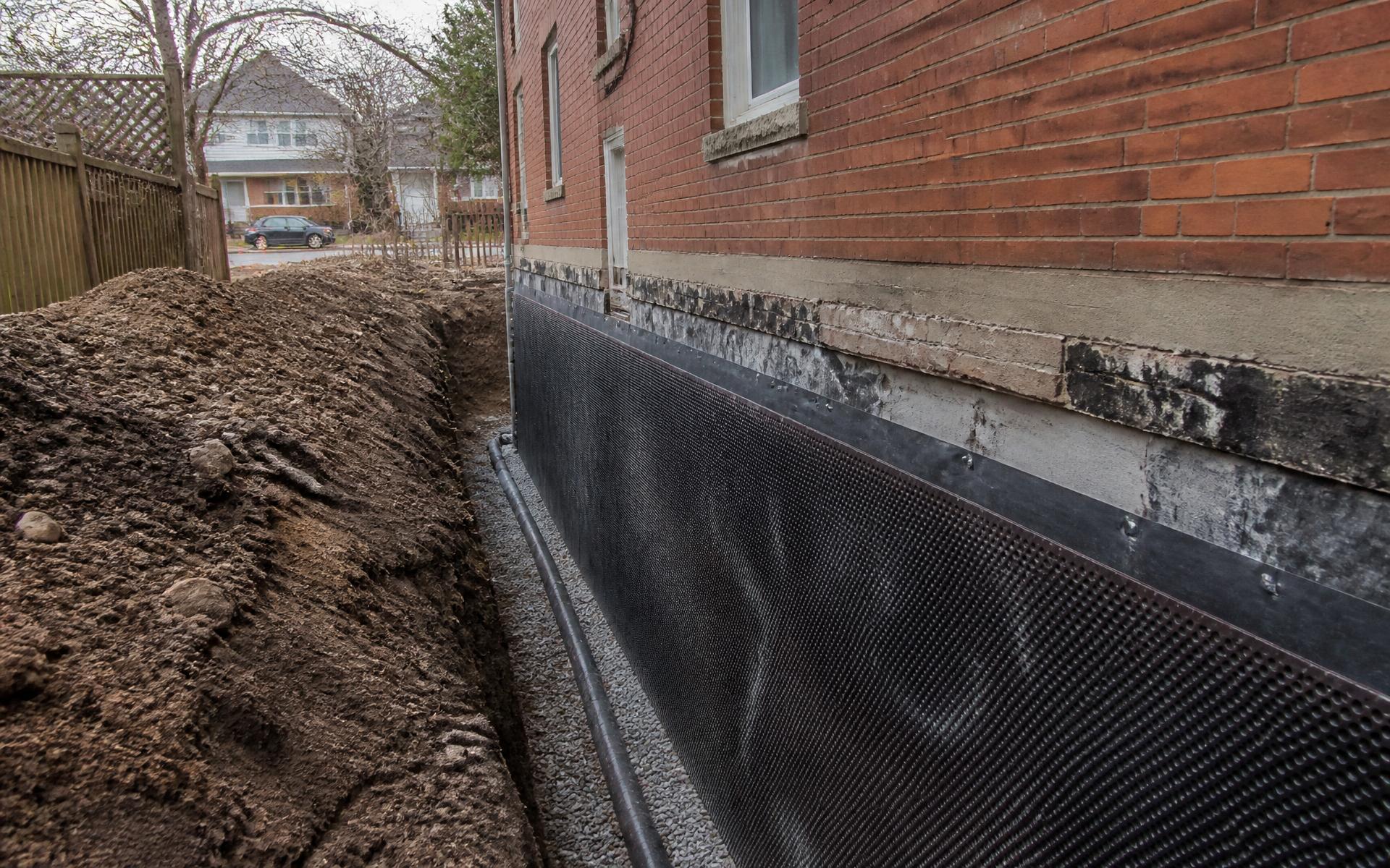 Excavated foundation wall of a Toronto brick home with waterproofing membrane installed